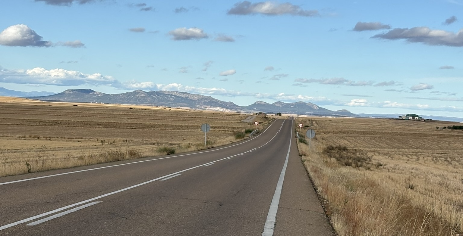 Distant view of rolling hills and mountains of the Sierra Norte de Sevilla, with multiple layers of terrain fading into the horizon under a bright sky.