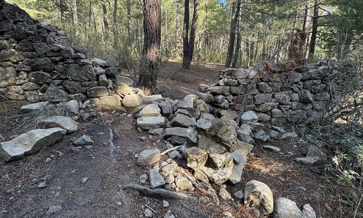 A gap in the stone wall of the Valle de Cuelgamuros, showing a rocky road ahead
